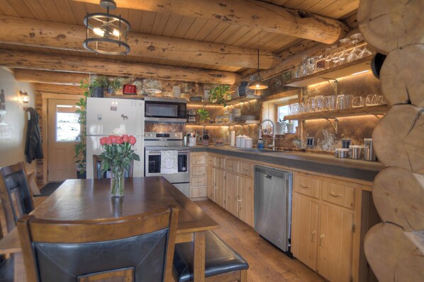 Una cocina rústica con armarios de madera, un refrigerador de acero inoxidable y una zona de comedor con una mesa y sillas de madera.