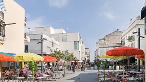 Eine Straße mit Außenplätzen, Sonnenschirmen und Häusern mit Balkonen.