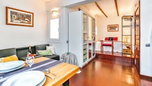 Ein modernes Wohnzimmer mit einem Holzes Esstisch, gedeckt für zwei Personen, einer Couch und einer Glasvitrine.