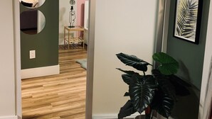 Un interior moderno con una puerta corredera que da a otra habitación, un espejo grande, una planta en maceta y obras de arte enmarcadas en la pared.