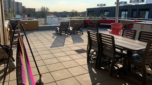 Un área de patio al aire libre con suelo de baldosas, mobiliario de madera y unidades de aire acondicionado.
