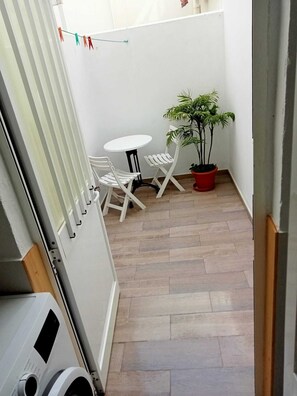 A small patio area with a white table and chairs, a potted plant, and a clothesline with colorful clothespins. - Casa Niebla        . (Vejer de la Frontera)