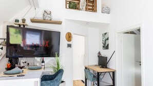 A modern living space with a TV, dining area, and workspace. - Premium Suite - Forest view - Balcony - Black Forest (Bühl)