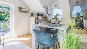 A modern kitchen with a dining area, a view of the outdoors, and a loft bedroom with a skylight. - Premium Suite - Forest view - Balcony - Black Forest (Bühl)