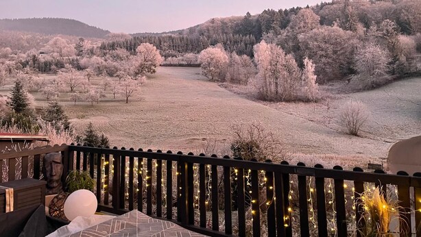 A balcony with a view of a frosty landscape, including trees and a field. - Premium Suite - Forest view - Balcony - Black Forest (Bühl)