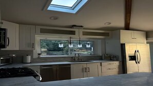 Een moderne keuken met dakraam, roestvrijstalen apparatuur en een groot raam.