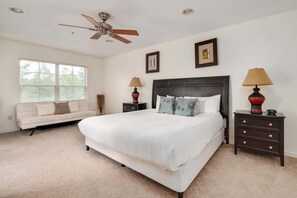 A bedroom with a bed, a nightstand, a lamp, a ceiling fan, and a window.