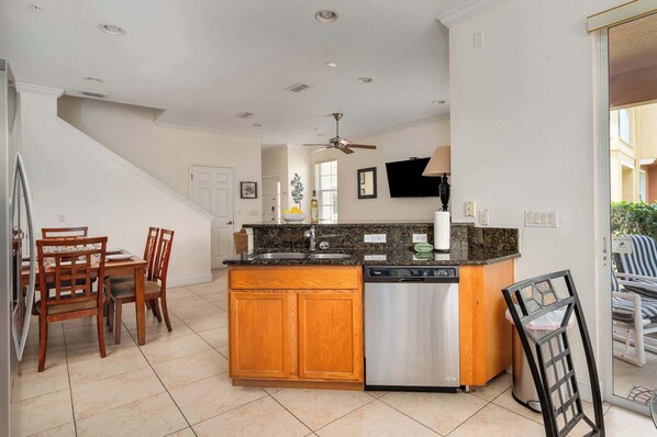 A kitchen with wooden cabinets, a built-in dishwasher, and a granite countertop.