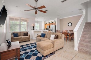 A spacious living room with a large sectional sofa, a ceiling fan, and a dining area with a table and chairs.