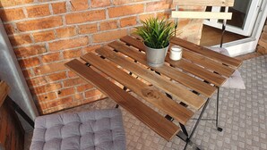 Een houten tafel met een metalen frame, een plant in pot en een kaars op een kamer met een patroon vloer.