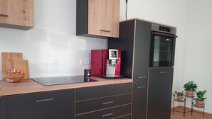 Een moderne keuken met een ingebouwde koffiemachine, een rode koelkast en houten keukenkastjes.