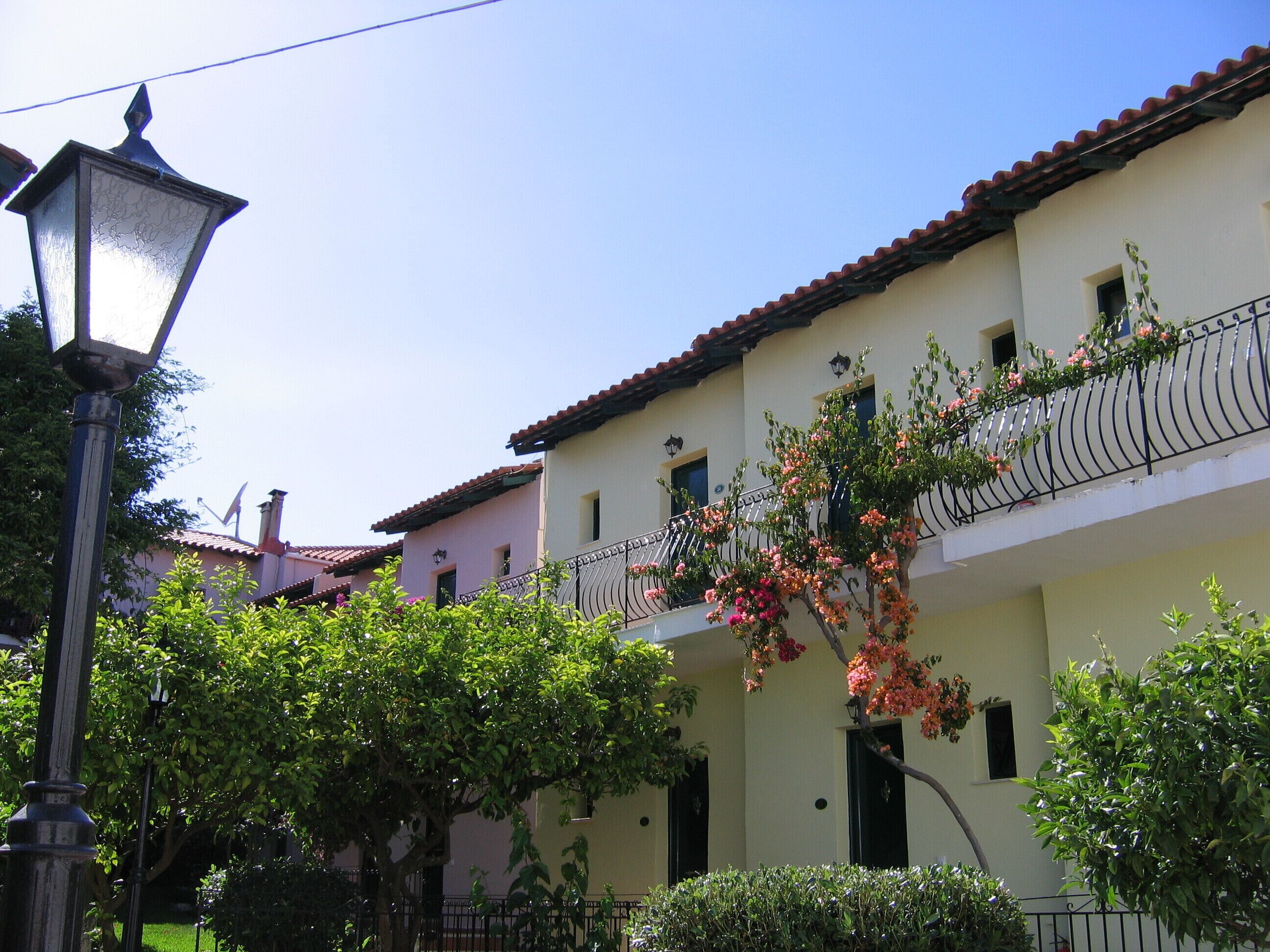 A building with a balcony, a street lamp, and lush greenery.