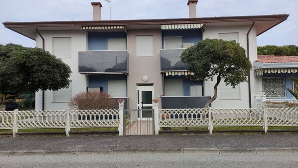 Un edificio de dos plantas con fachada simétrica, una entrada central con puerta y un pequeño porche.