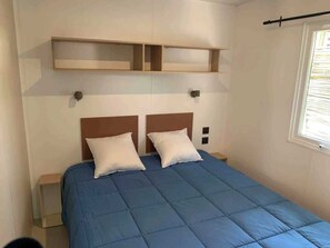 Une chambre à coucher avec un lit, deux tables de chevet et des étagères intégrées au-dessus du lit.
