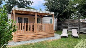 A wooden deck with a pergola, two white chairs, and a small table. - ZEcamping 3 étoiles piscine chauffée animaux acceptés mobil-home TV LV (Verruyes)
