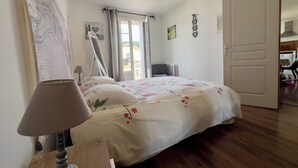 Een slaapkamer met een bed, een lamp, een spiegel en een deur die uitkomt op een balkon.