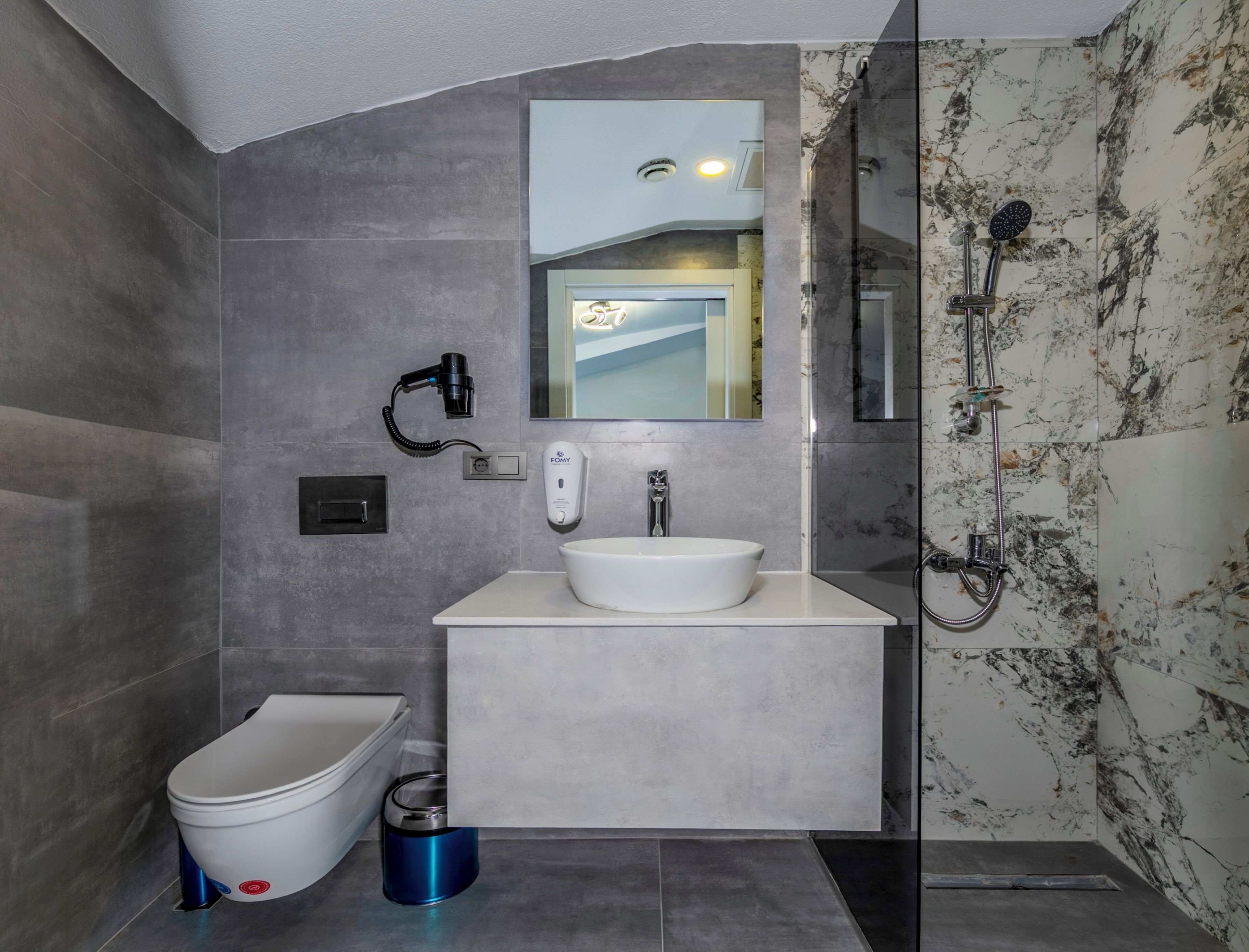 A modern bathroom with a toilet, bidet, and a glass-enclosed shower area.