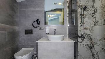 A modern bathroom with a toilet, bidet, and a glass-enclosed shower area.