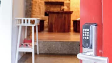 Un vestíbulo moderno con una puerta roja, un candado con teclado numérico y una pequeña silla blanca.