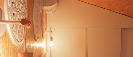 A bedroom with a wooden headboard, a wall-mounted air conditioner, and a bedside lamp.