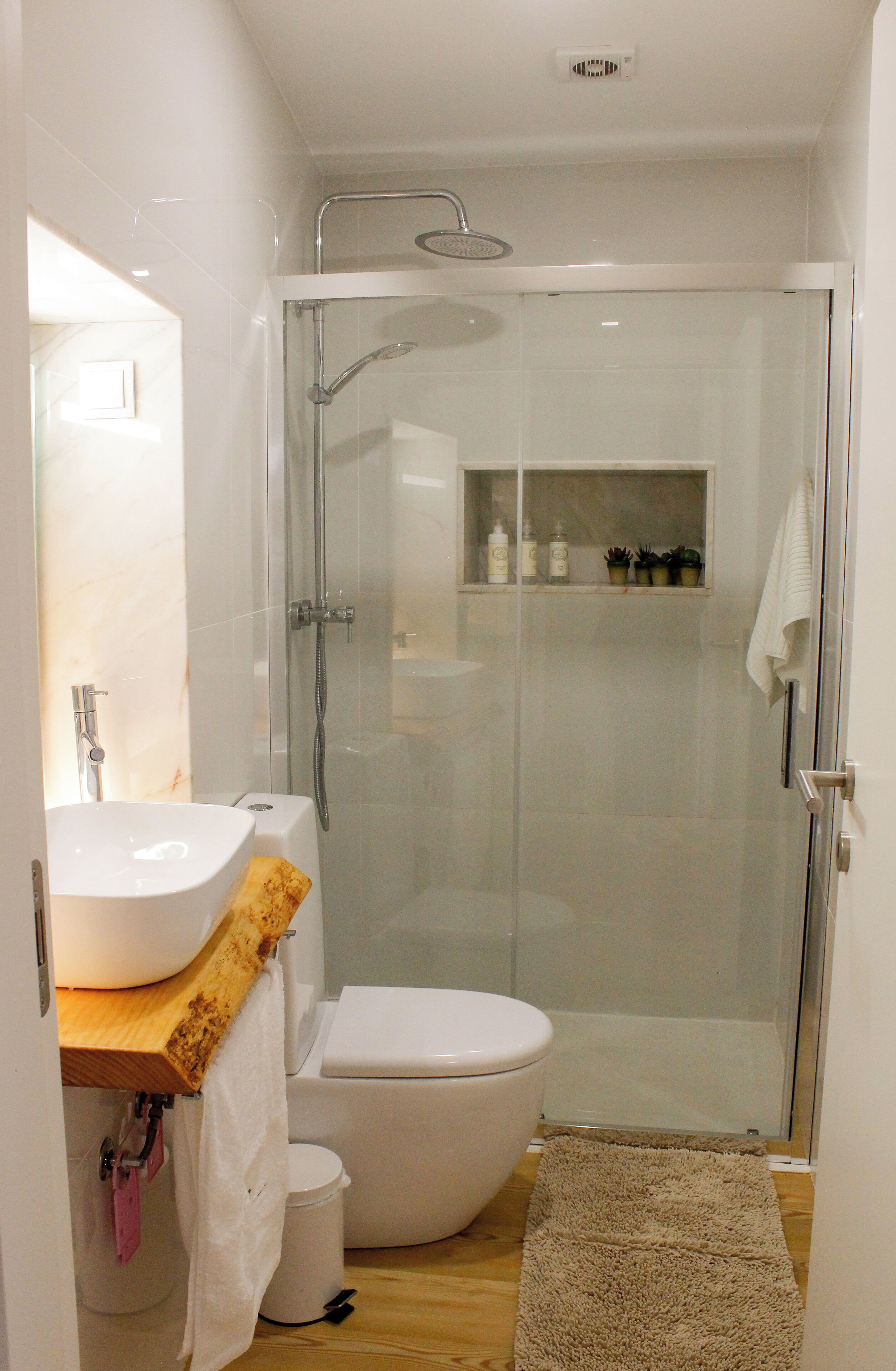 A modern bathroom with a glass-enclosed shower, a white sink, and a toilet.