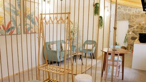 A room with a hanging chair, a sofa, a small table, and a stone wall. - Villa Garcia (Terras de Bouro)