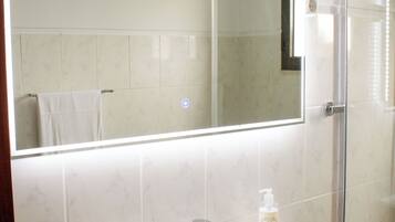 Un baño con un lavabo blanco, un espejo y una planta en maceta.