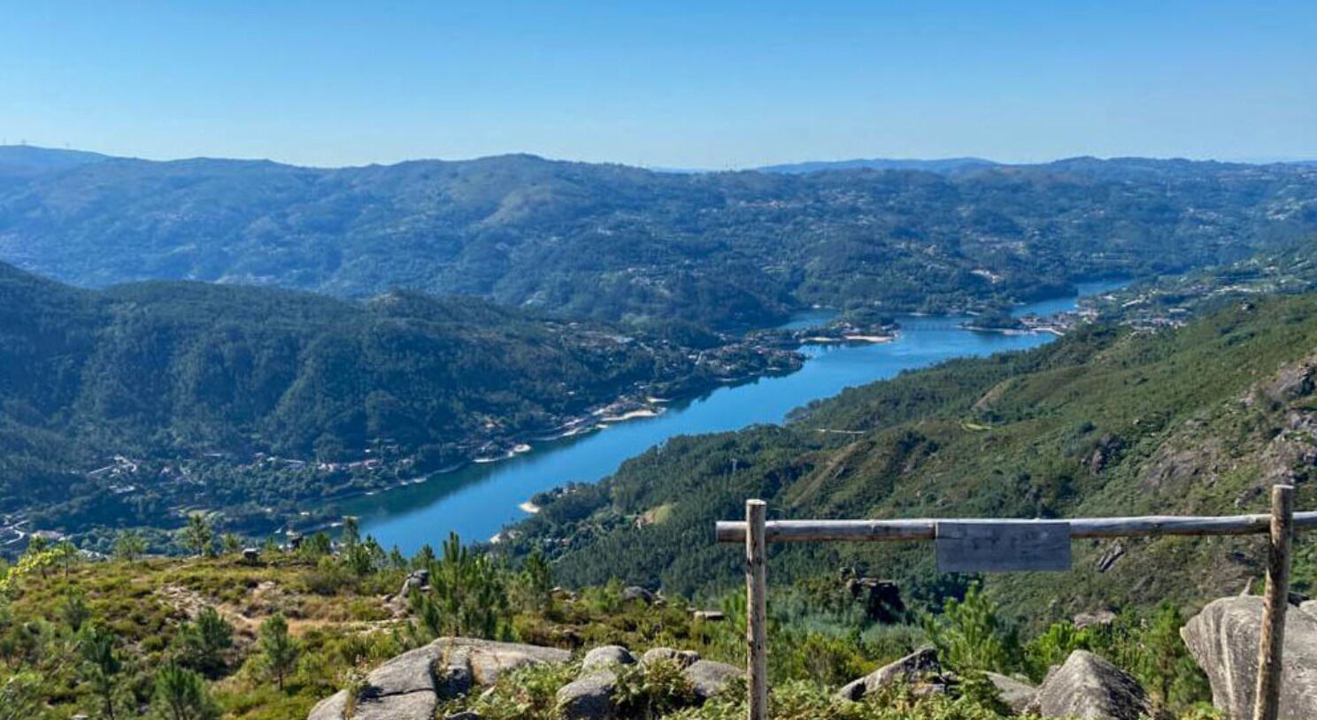 A mountainous landscape with a lake and a wooden signpost in the foreground.