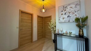 A hallway with wooden doors, a black console table with decorative items, and a ceiling light fixture. - Villa Garcia (Terras de Bouro)