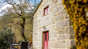 A stone building with a red door and window, surrounded by trees. - Villa Garcia (Terras de Bouro)