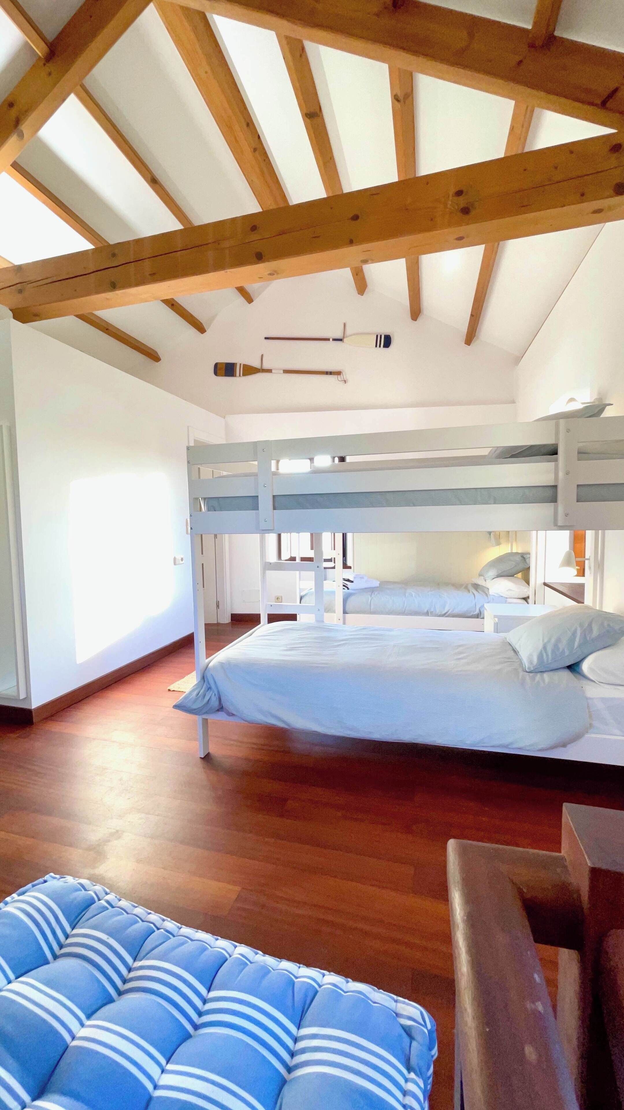 A room with a bunk bed, a wooden ceiling, and a small table.