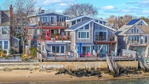 Una casa a più piani sulla costa, con un balcone, una terrazza e vista sulla spiaggia.