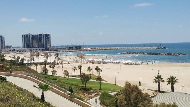 A coastal beach area with a promenade, palm trees, and a view of the sea. - Herzlia Pituah apartment with Pool, by the Acadia Beach! (Herzliya)