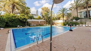 A swimming pool with lounge chairs, a shower, and palm trees. - Herzlia Pituah apartment with Pool, by the Acadia Beach! (Herzliya)