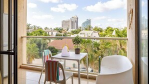 A balcony with a table, chairs, and a potted plant. - Herzlia Pituah apartment with Pool, by the Acadia Beach! (Herzliya)