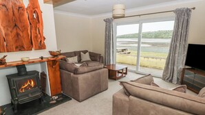 Una sala de estar acogedora con chimenea, sofás y un amplio ventanal con vista al agua.