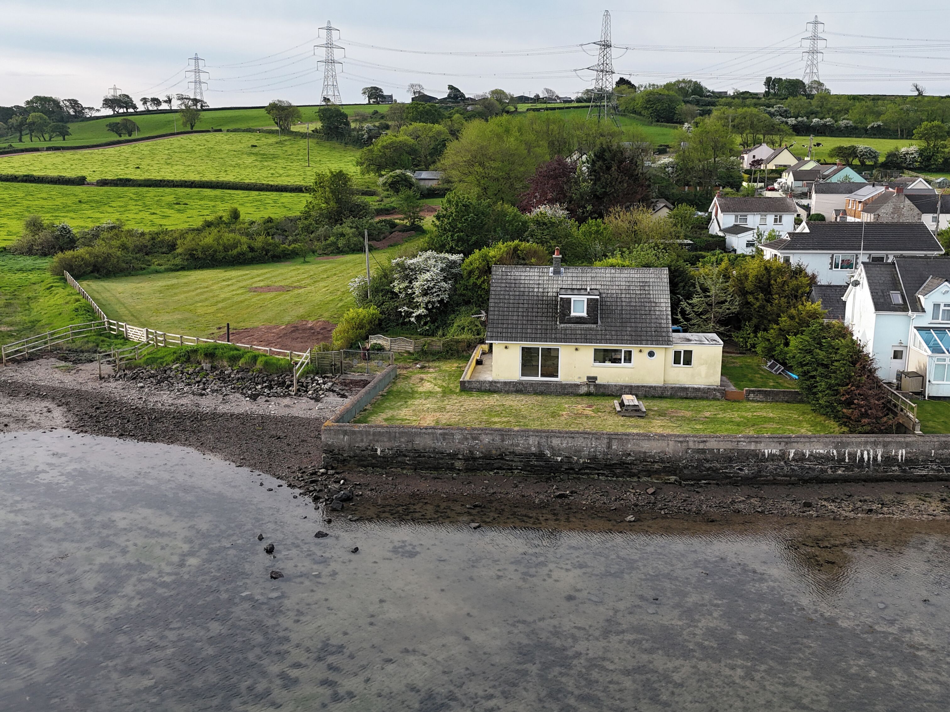 A coastal village with houses, a grassy field, and a rocky shoreline.