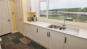Una cocina con vista a un lago por la ventana, armarios blancos, un fregadero y un tostador.