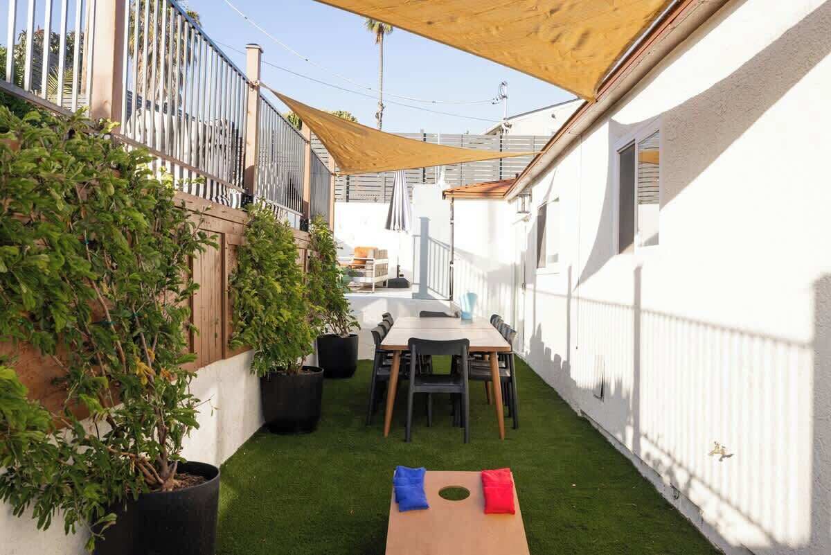 A narrow outdoor patio with a table and chairs, surrounded by white walls and a wooden fence.
