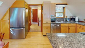 Una cocina moderna con refrigerador de acero inoxidable, horno empotrado y encimeras de granito.