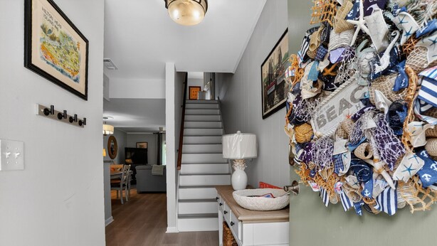 Una escalera que lleva al segundo piso, una pared blanca con un cuadro enmarcado y una pared decorada con varios textiles.