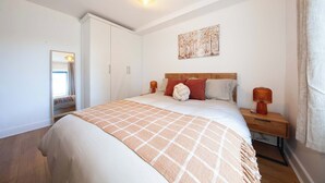 A bedroom with a bed, a nightstand, a lamp, a painting on the wall, and a wardrobe. - Stylish and trendy 2bed apartment in city centre. (Dublin)