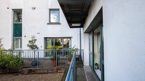 A narrow outdoor corridor with a metal railing, potted plants, and a wooden log border. - Stylish and trendy 2bed apartment in city centre. (Dublin)