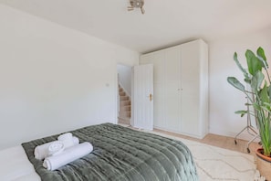 A bedroom with a bed, a large wardrobe, a staircase, and a potted plant. - Luxuriously Curated 4BD Home, Stoke Newington (Greater London)