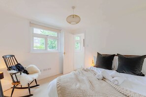 A bedroom with a bed, a rocking chair, a window, and a door.