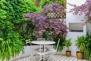 A round table with four chairs, surrounded by potted plants and a checkered floor. - Luxuriously Curated 4BD Home, Stoke Newington (Greater London)