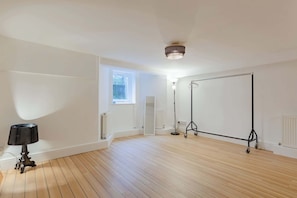 A room with wooden flooring, a standing lamp, a projector screen, and a window. - Luxuriously Curated 4BD Home, Stoke Newington (Greater London)