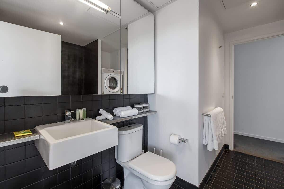 Ein modernes Badezimmer mit einem großen Waschbecken, Toilette und einem Spiegel darüber.