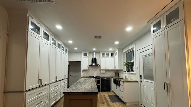 A modern kitchen with white cabinets, a wooden countertop, and a central island.
