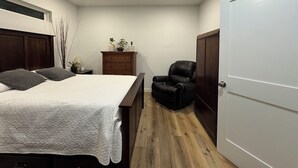 A bedroom with a bed, a dresser, a chair, and a wardrobe.